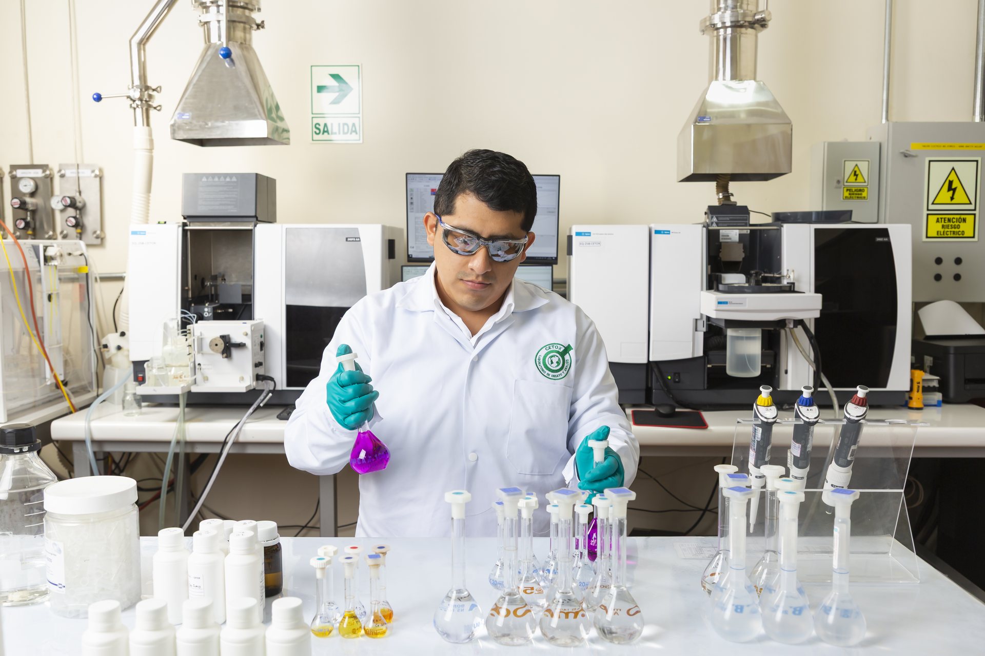 Analista de CETOX LAB preparando estándares junto a los espectrómetros de absorción atómica